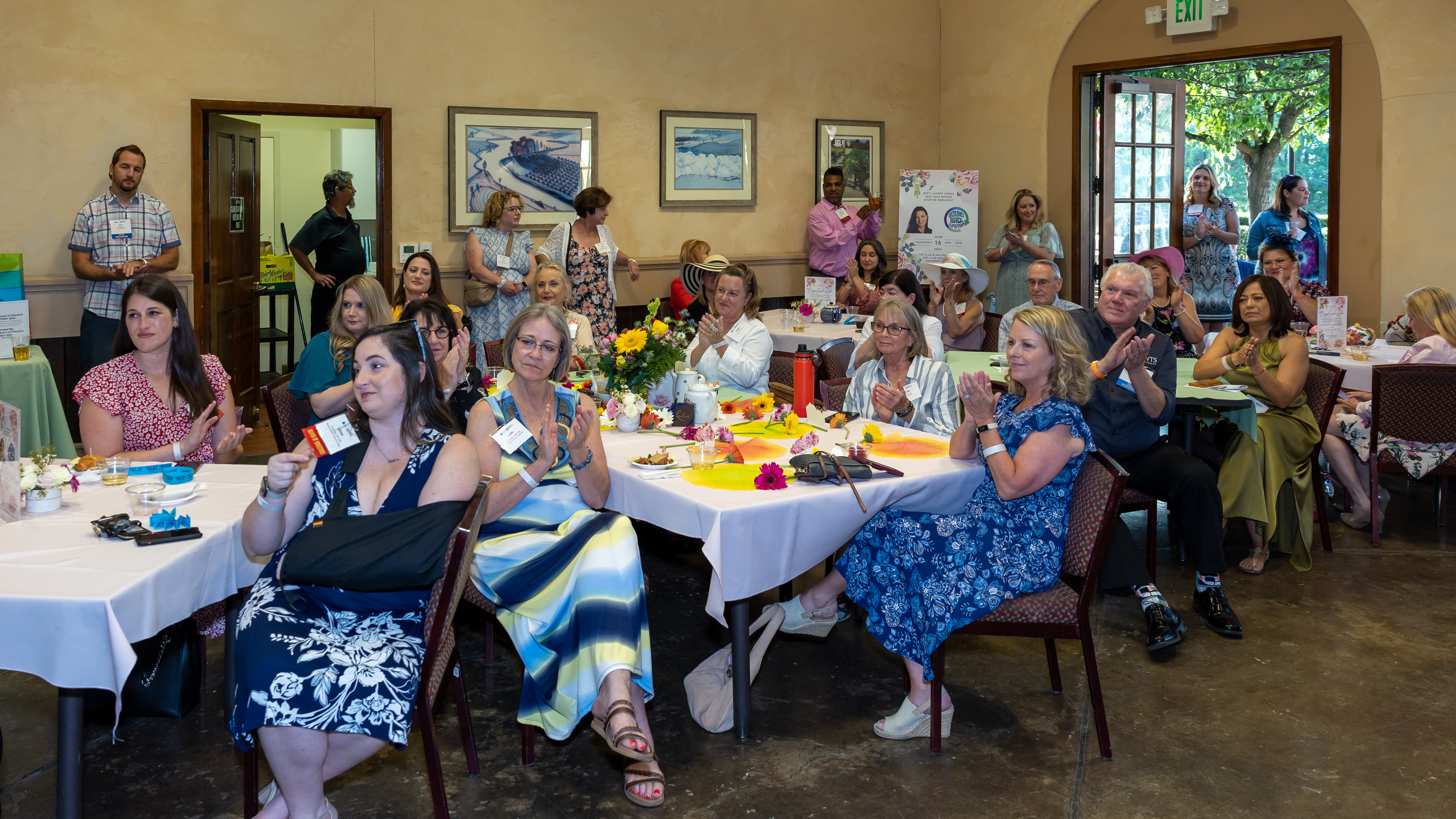 Group of MPISSN members sitting at tables and clapping at the recent MPISSN Gala